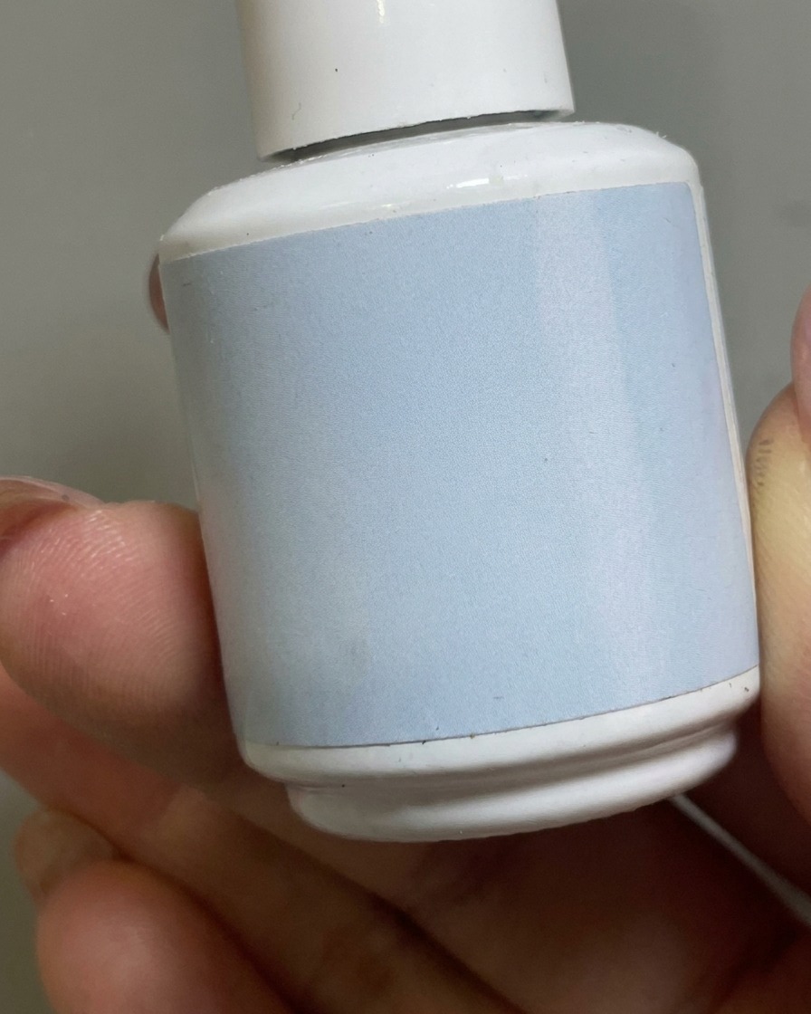 Un pincel aplicando un top coat mate transparente sobre la base nude en una uña.