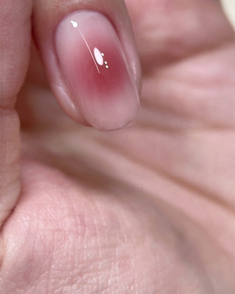 Primer plano de un dedo con un centro de gel rosa vino tipo blush colocado dentro de una lámpara UV para curar.