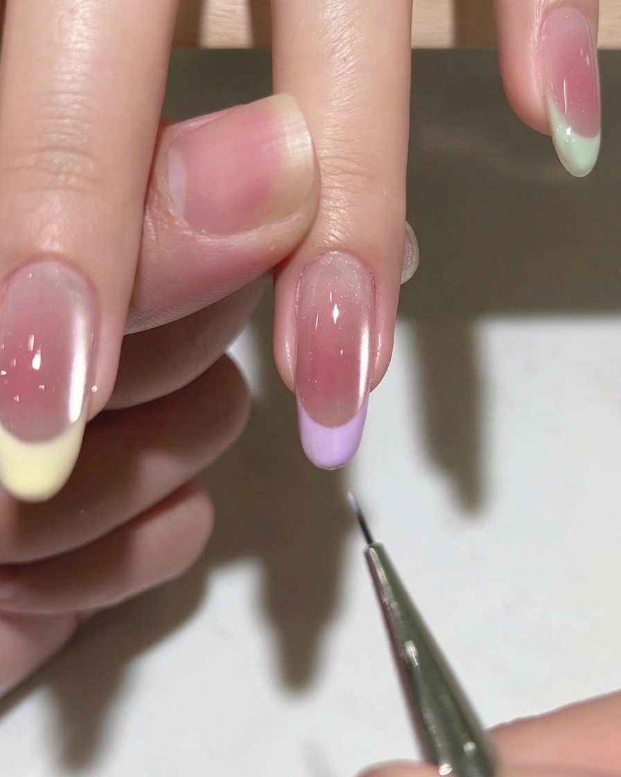 Primer plano de un pincel de uñas aplicando una base de gel transparente sobre una uña natural limpia y preparada.