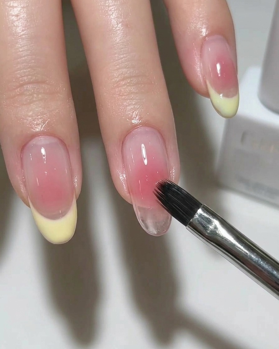Un pincel aplicando un esmalte magnético plateado brillante sobre la base de la uña.