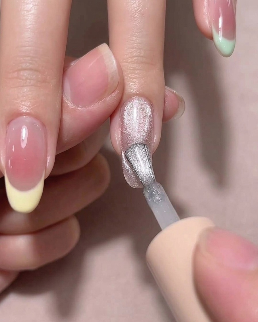 Una herramienta magnética sostenida cerca de una uña con esmalte húmedo para crear un efecto de brillo diagonal.