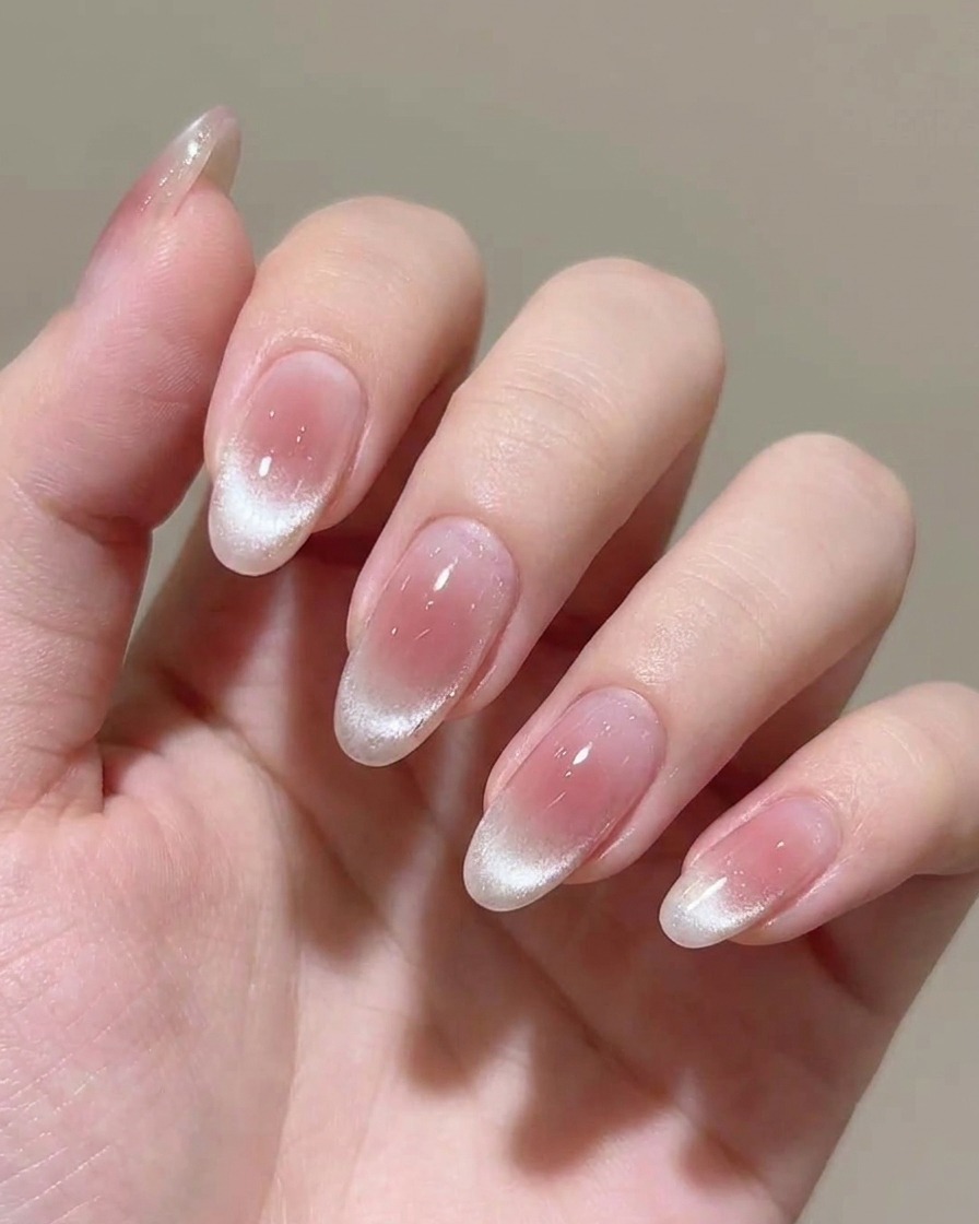 Aplicando una segunda capa de esmalte en gel rosa translúcido en la uña.