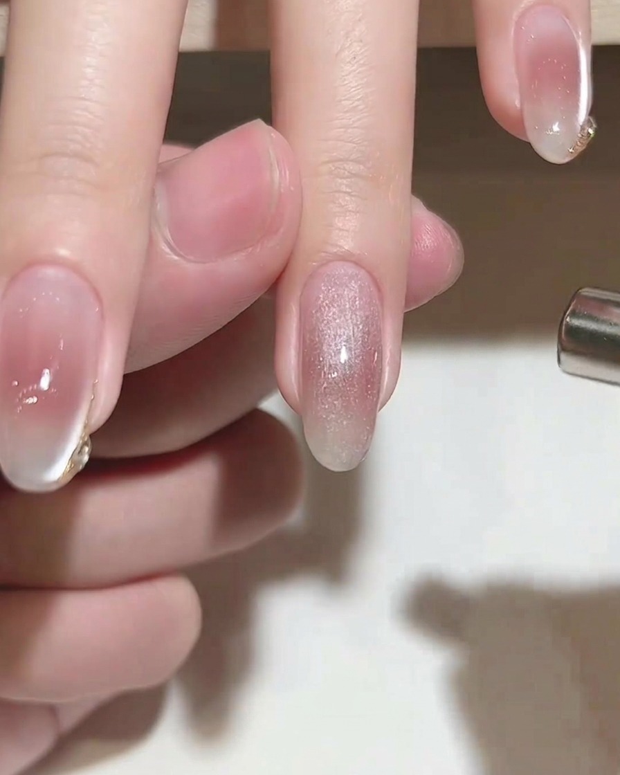 Un imán cilíndrico sobre una uña cubierta con gel cat eye húmedo para crear un efecto brillante.