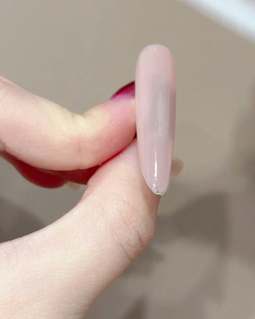 Una toallita libre de pelusa limpiando la superficie de una uña de gel curada.