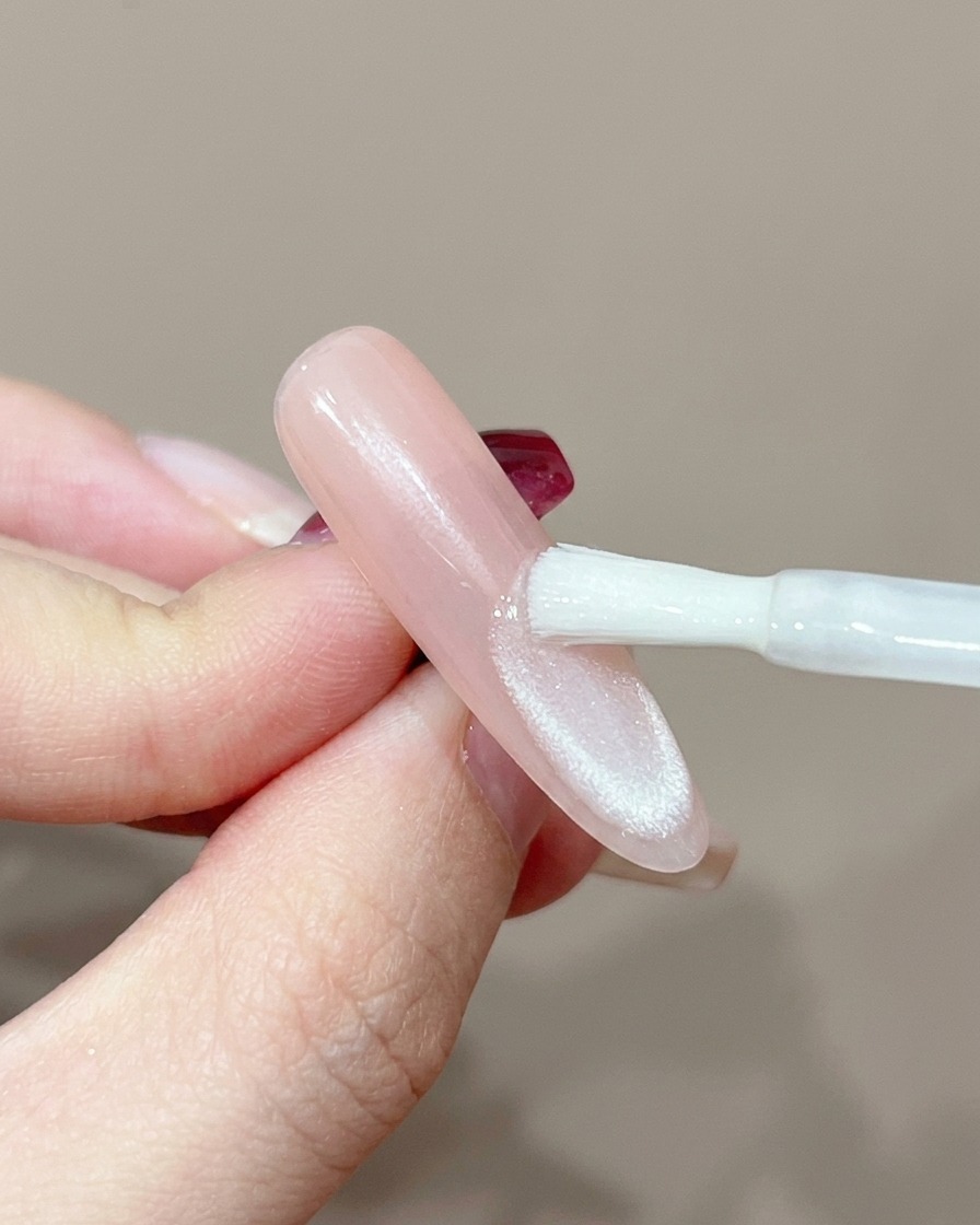Una uña posicionada bajo una lámpara UV profesional para curado.