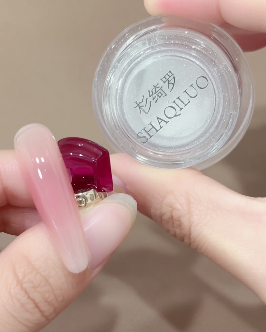Una herramienta con punta de silicona recogiendo una pequeña cantidad de polvo cromo iridiscente de un frasco.
