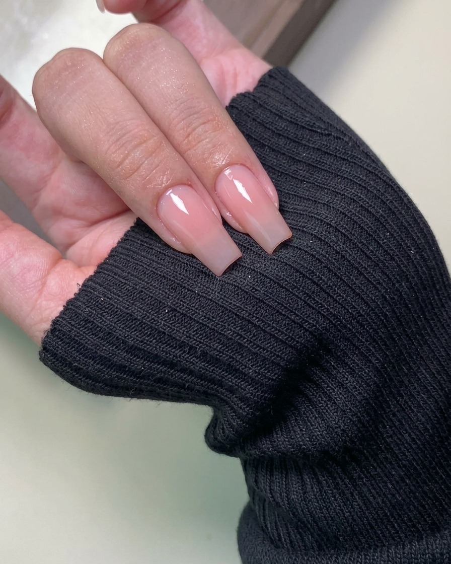Primer plano de una toallita sin pelusa limpiando la superficie de una uña manicurada.