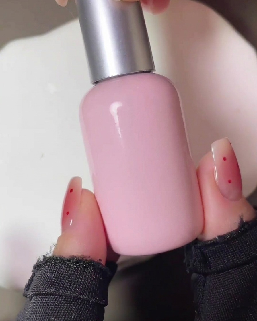 Las uñas curándose bajo una lámpara UV tras la aplicación inicial del pigmento rojo tipo rubor.