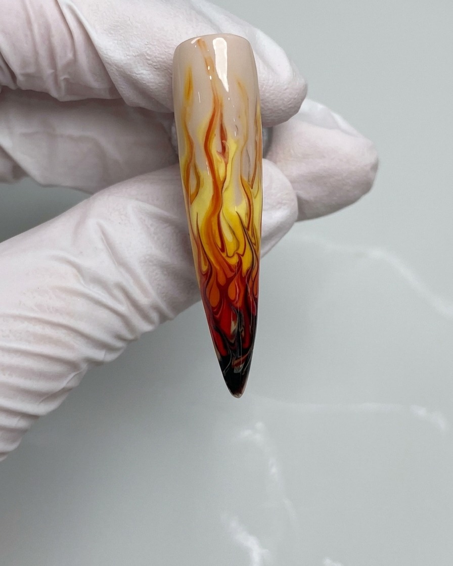 Un pincel de uñas aplicando esmalte de gel negro en la punta de una uña.