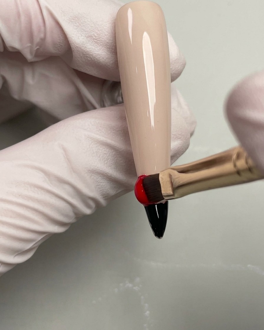 Esmalte de gel naranja aplicado sobre la sección roja en una uña.