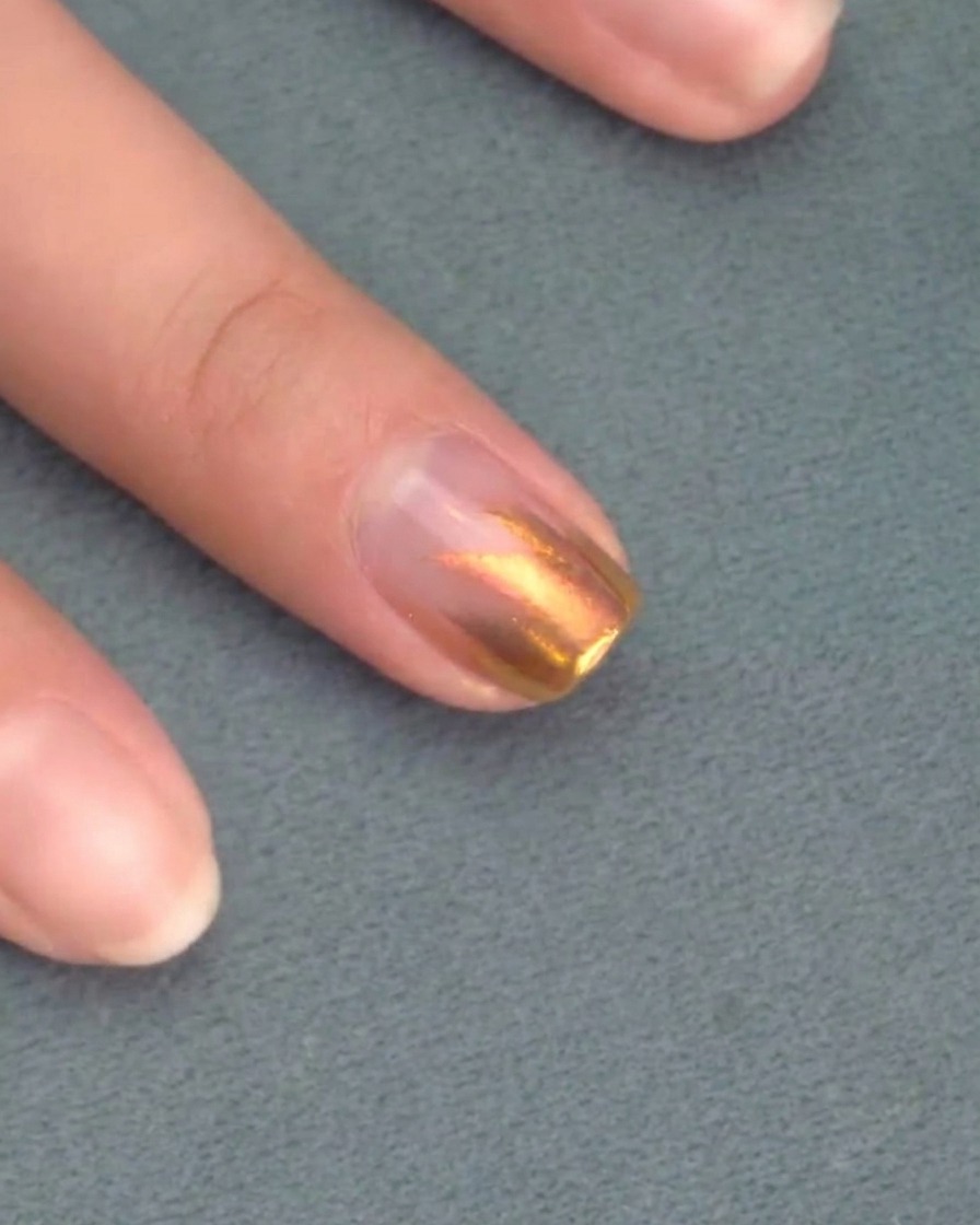 Un pincel aplicando una segunda capa de esmalte de gel rosa sobre la anterior.