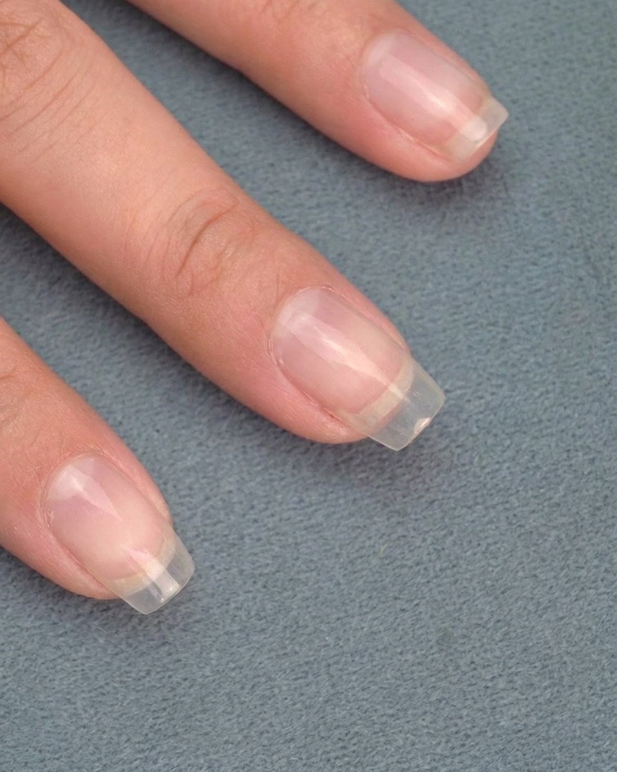 Primer plano de una herramienta puliendo el polvo cromo para revelar un acabado metálico tipo espejo en las uñas.