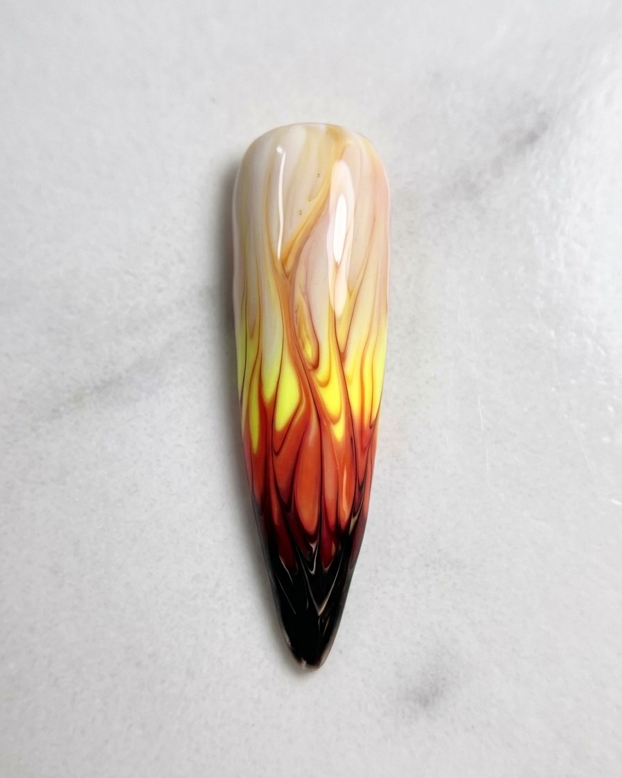 Vista desde arriba del diseño de nail art de llamas terminado, perfectamente difuminado y listo para el proceso de curado.