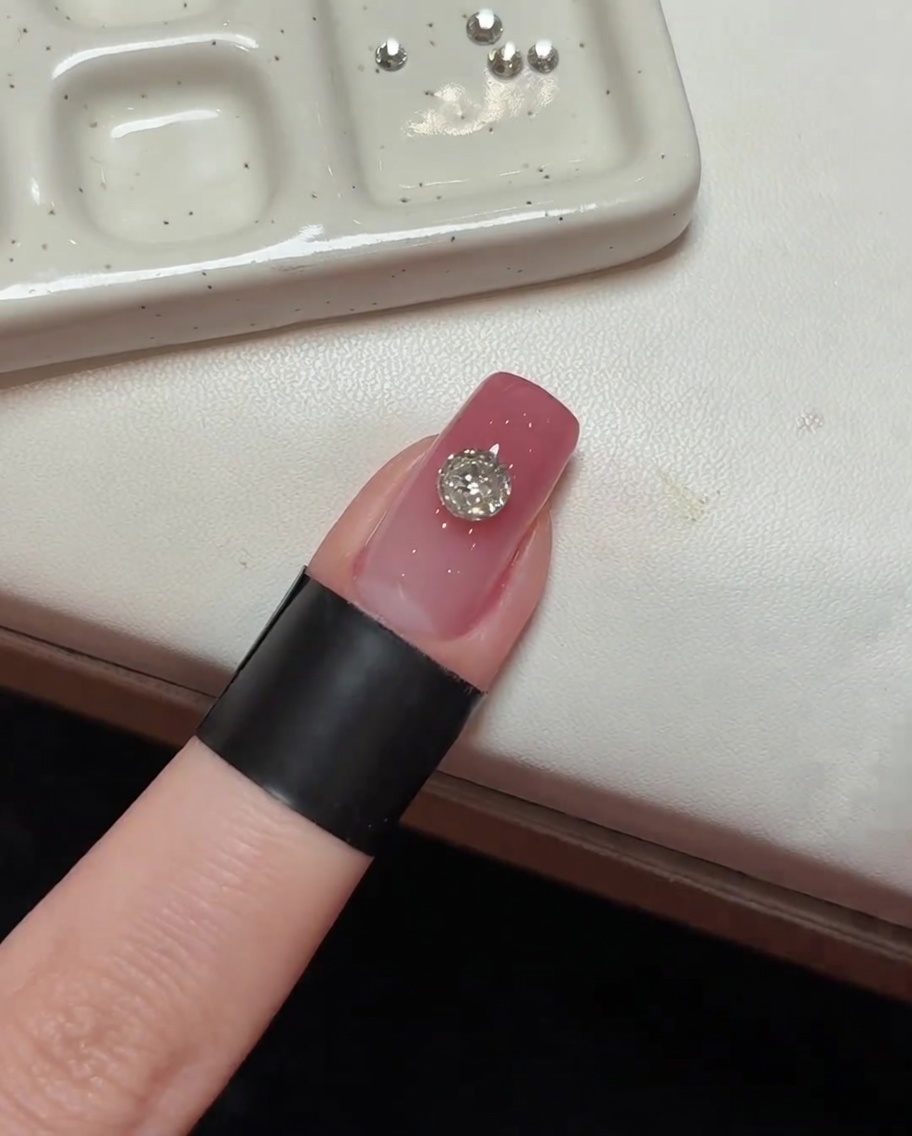 El cristal principal colocado en una uña rosa, posicionado bajo luz UV.