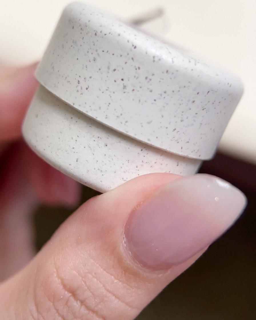 Primer plano de un frasco decorativo de gel con purpurina sostenido entre los dedos.