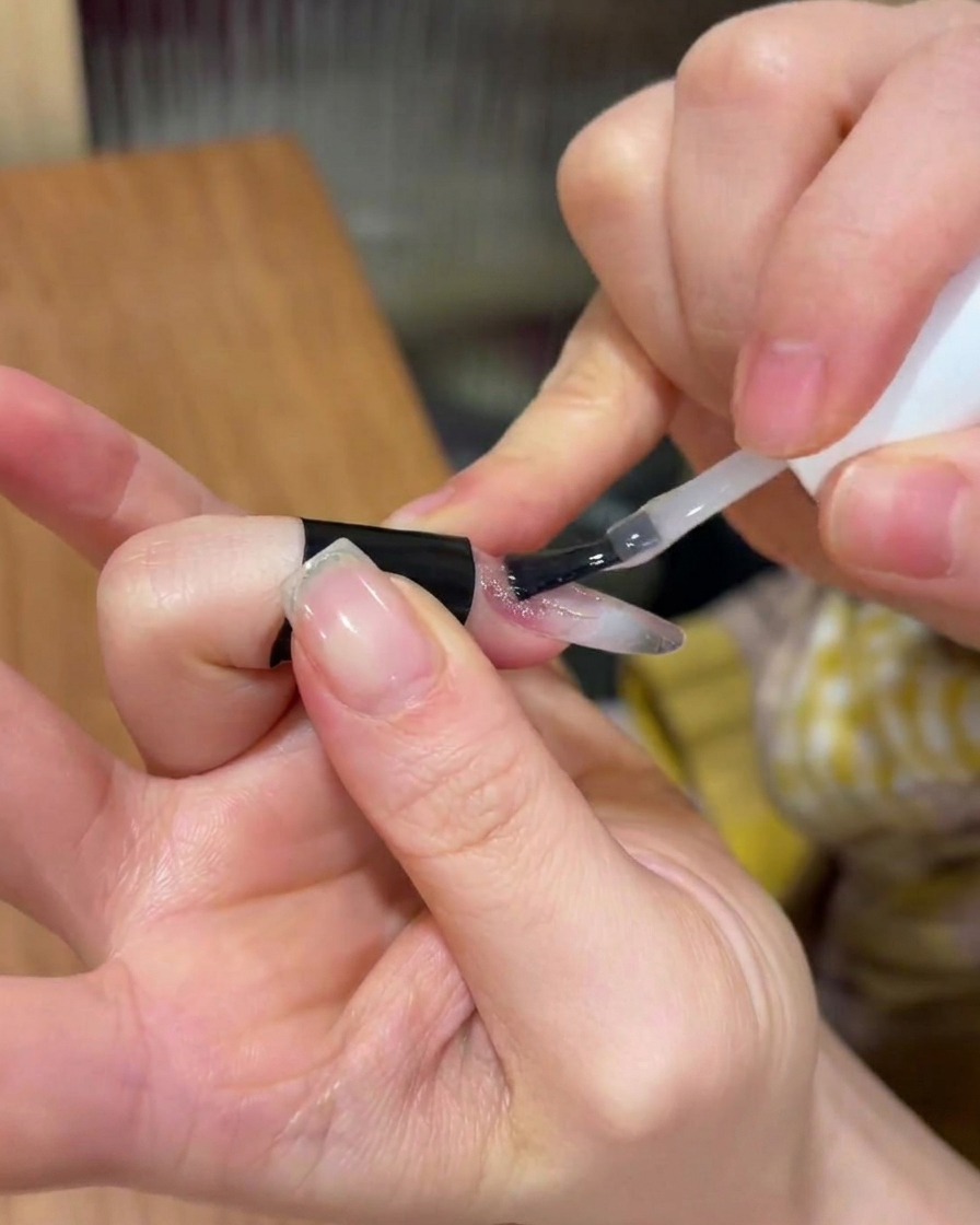 Aplicando una capa transparente de gel de construcción sobre el diseño de uñas existente.