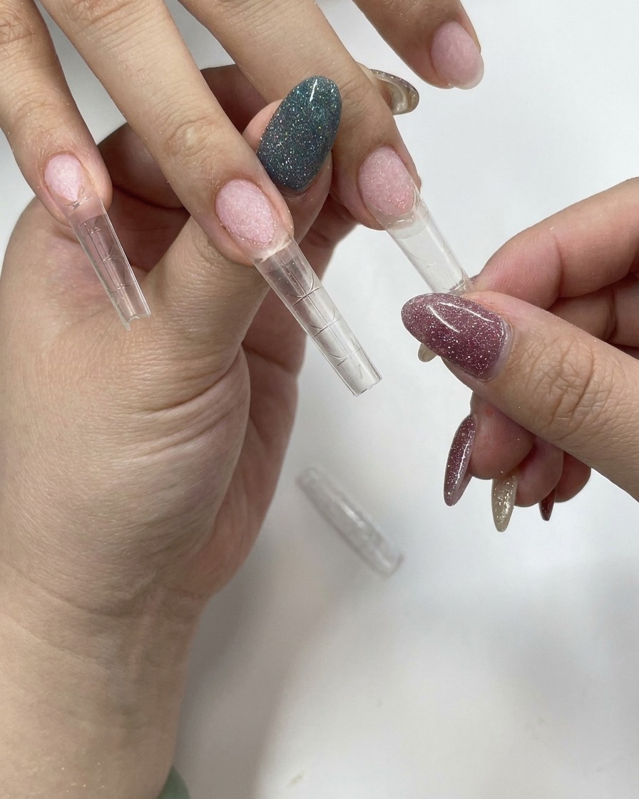 Una mano presionando firmemente un tip de uña transparente sobre una uña natural.