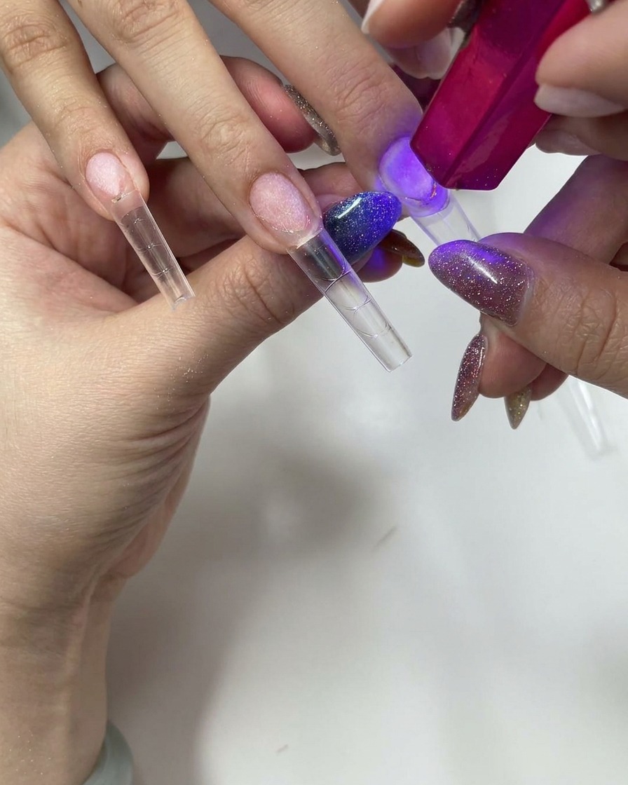 Uso de una lámpara UV/LED pequeña de mano para curar un tip de uña transparente.