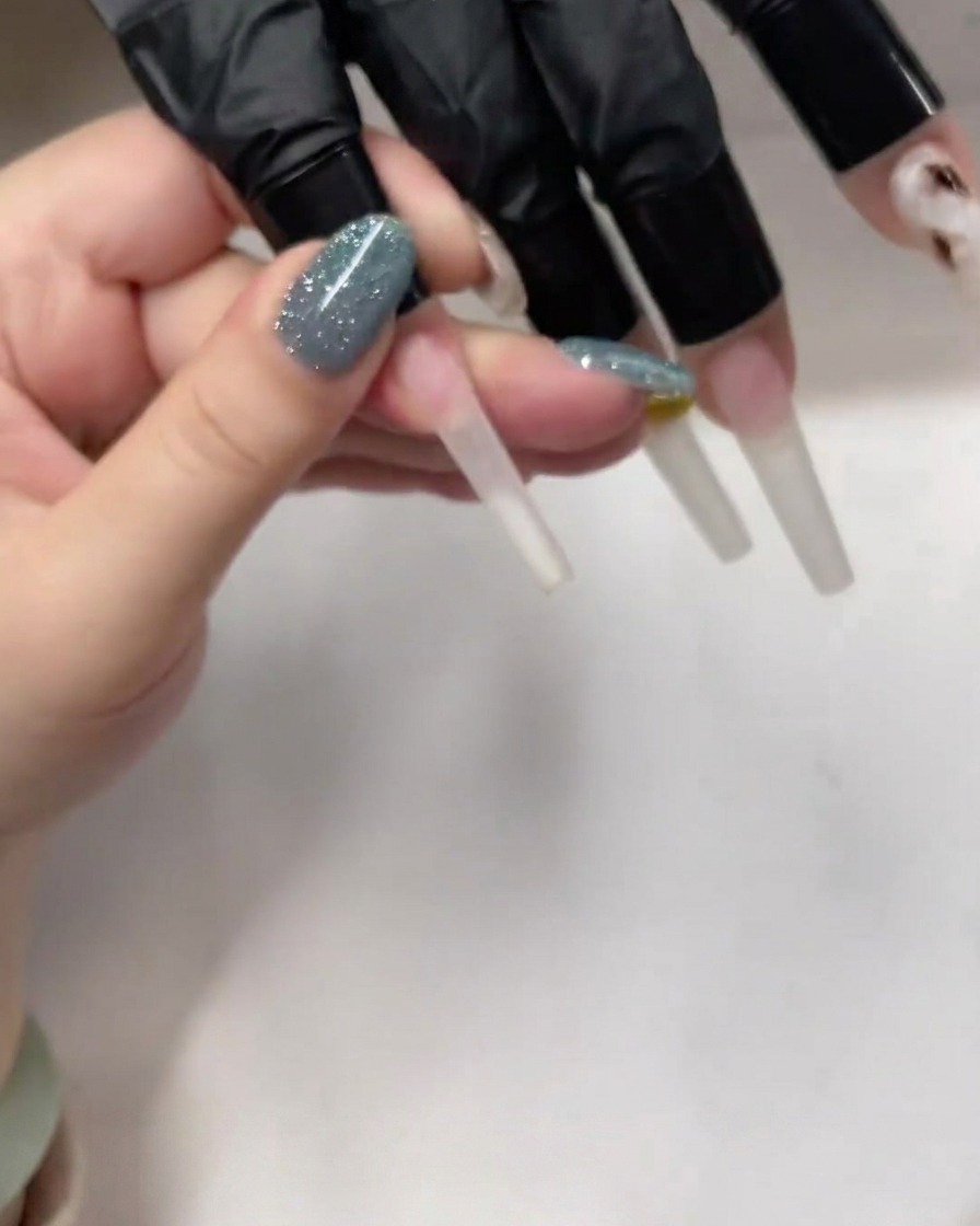 Imagen detallada de un pincel aplicando una capa fina de base gel transparente sobre una uña larga estilo coffin.