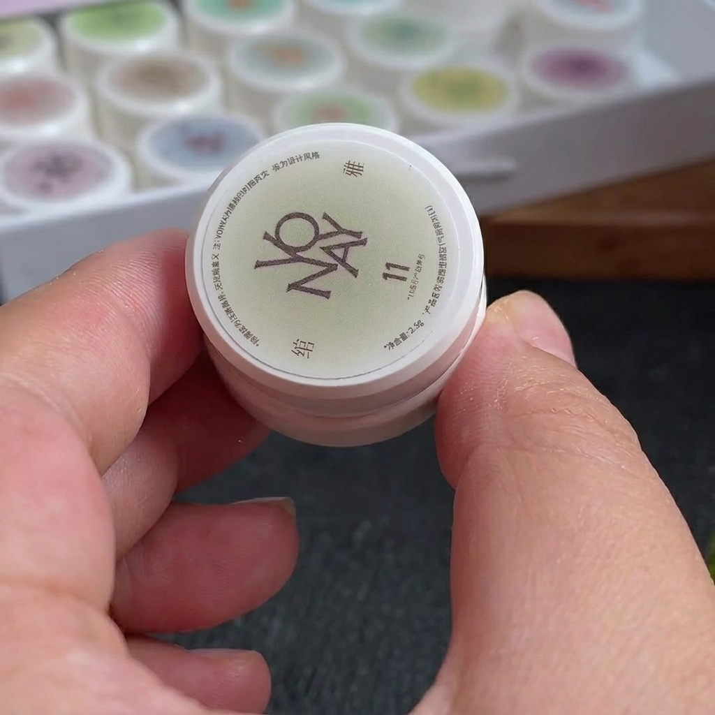 Una pequeña esponja de maquillaje con líneas de esmalte en gel blanco y rojo rosado aplicadas en su superficie.