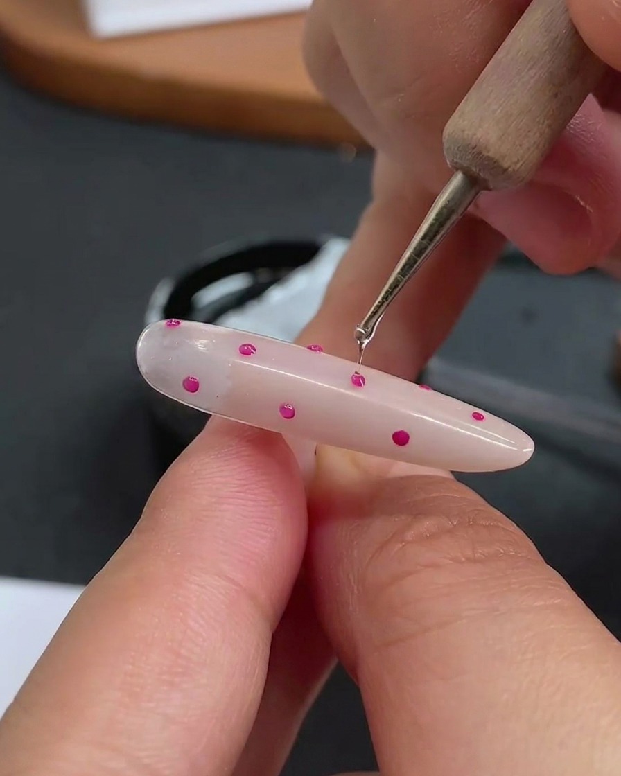 Un punzón aplicando una pequeña gota transparente de gel constructor sobre cada punto individual.