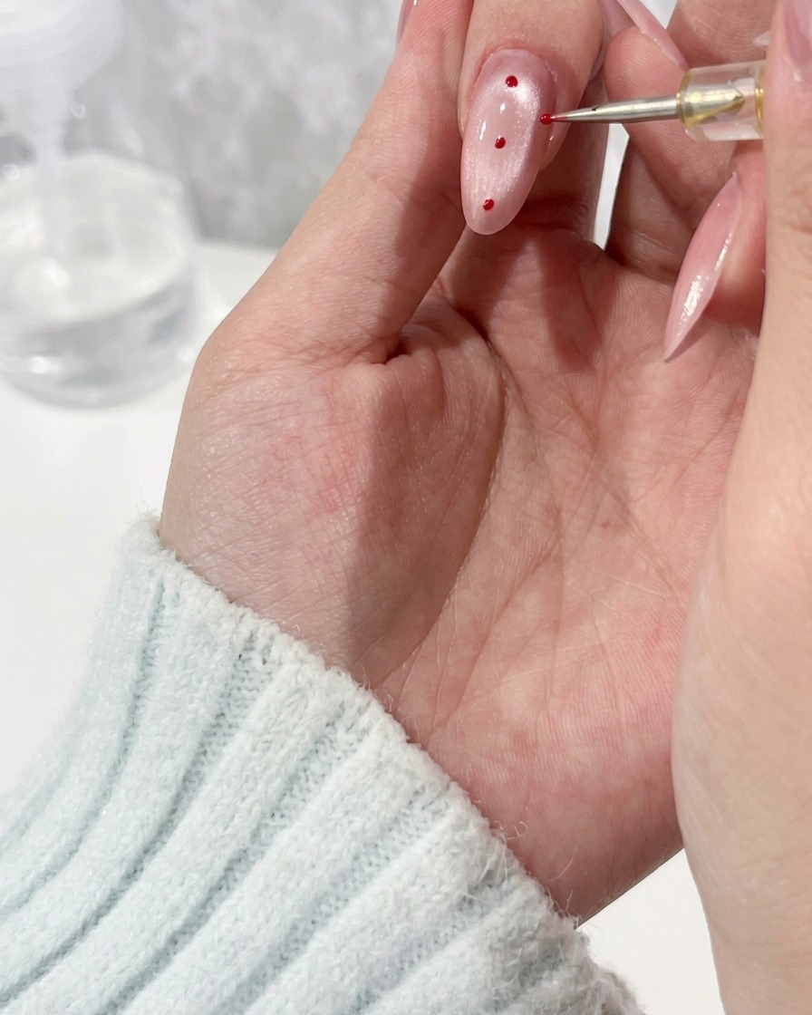 Vista cercana de un pincel de detalle aplicando una gota de gel transparente sobre una uña manicurada.