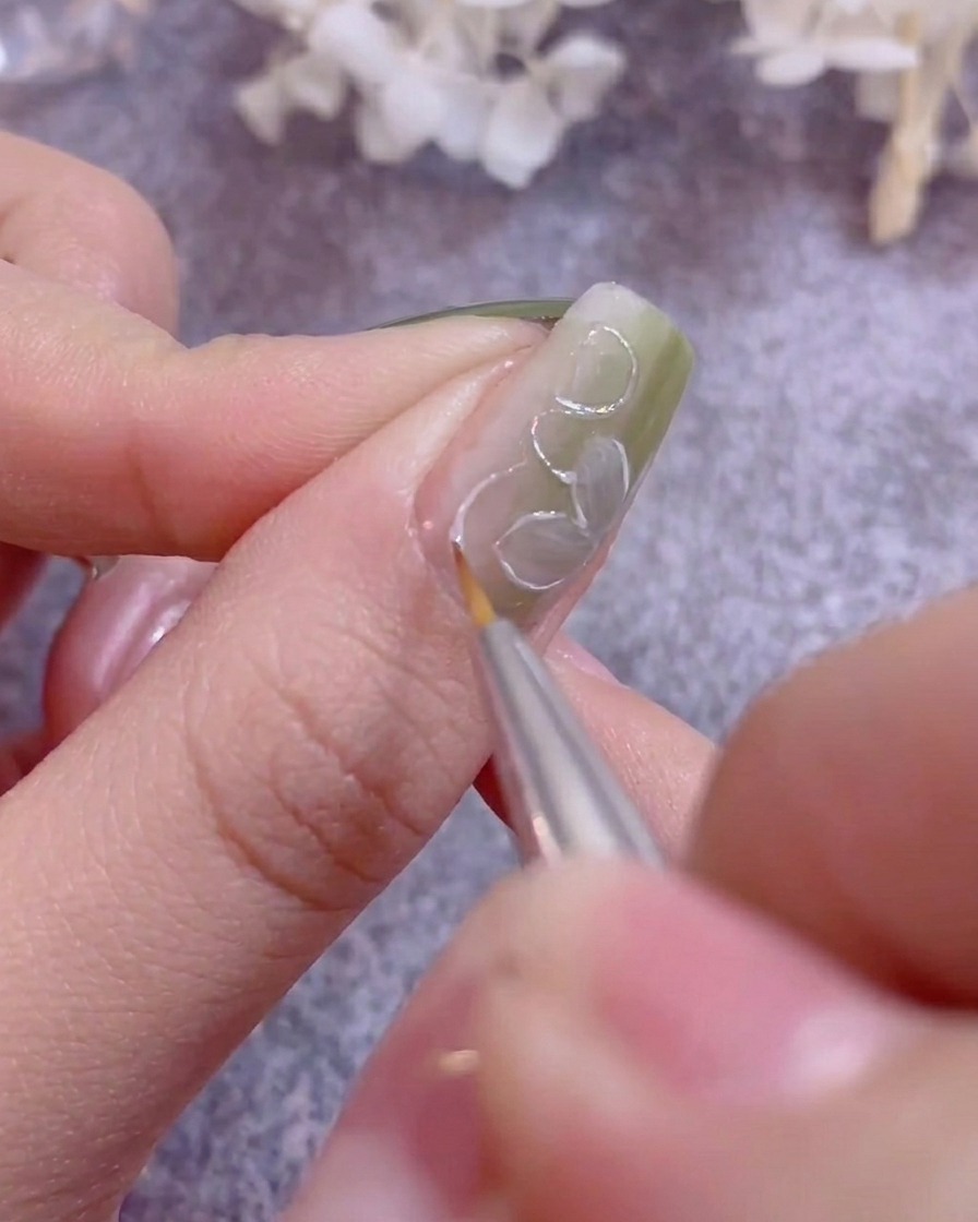 Una mano descansando bajo la luz púrpura de una lámpara UV/LED curando esmalte de gel.