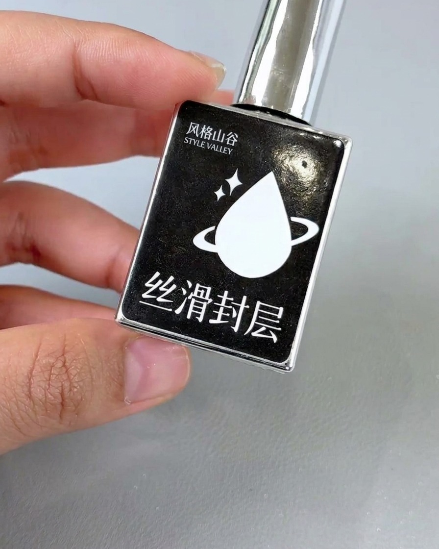 Un pincel de esmalte de uñas aplicando un top coat transparente y brillante sobre un diseño de uñas floral terminado.