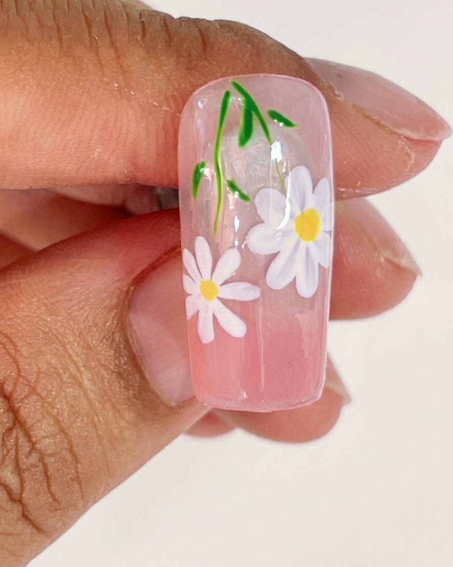 Un tip de uña colocado dentro de una lámpara UV para curar los pétalos blancos recién pintados.