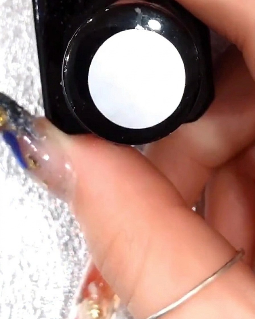 Primer plano de un pincel aplicando una capa delgada de gel transparente sobre el arte de pétalos.