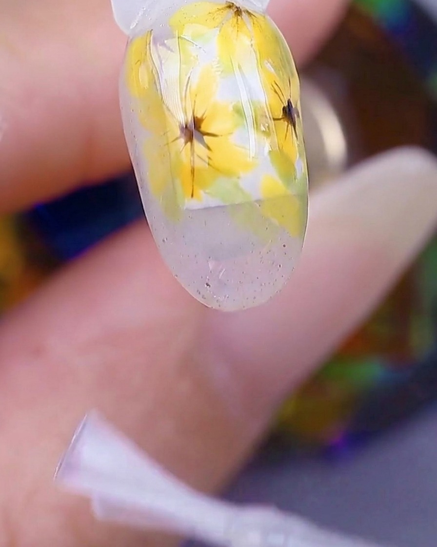Primer plano de una mano dentro de una lámpara de uñas UV/LED, con la superficie de la uña viéndose brillante bajo la luz.