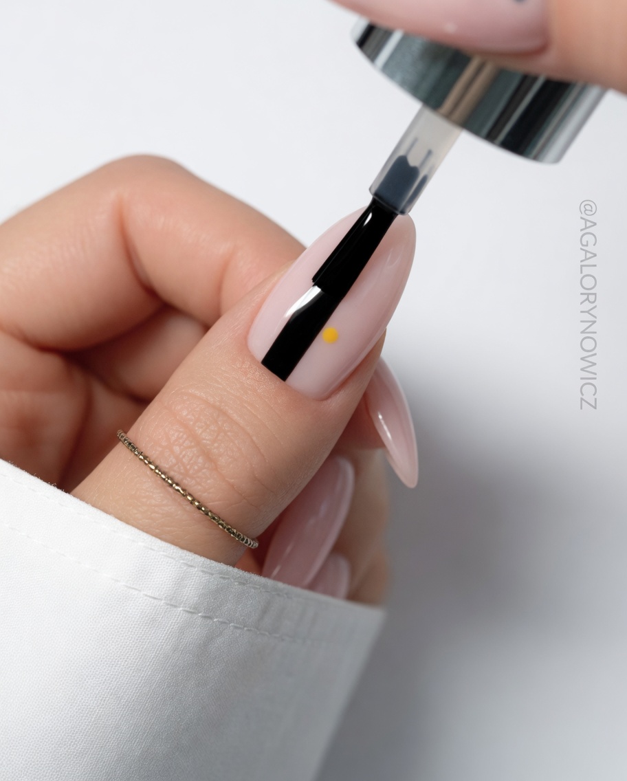 Imagen de detalle de un tercer pétalo blanco siendo pintado en la uña.