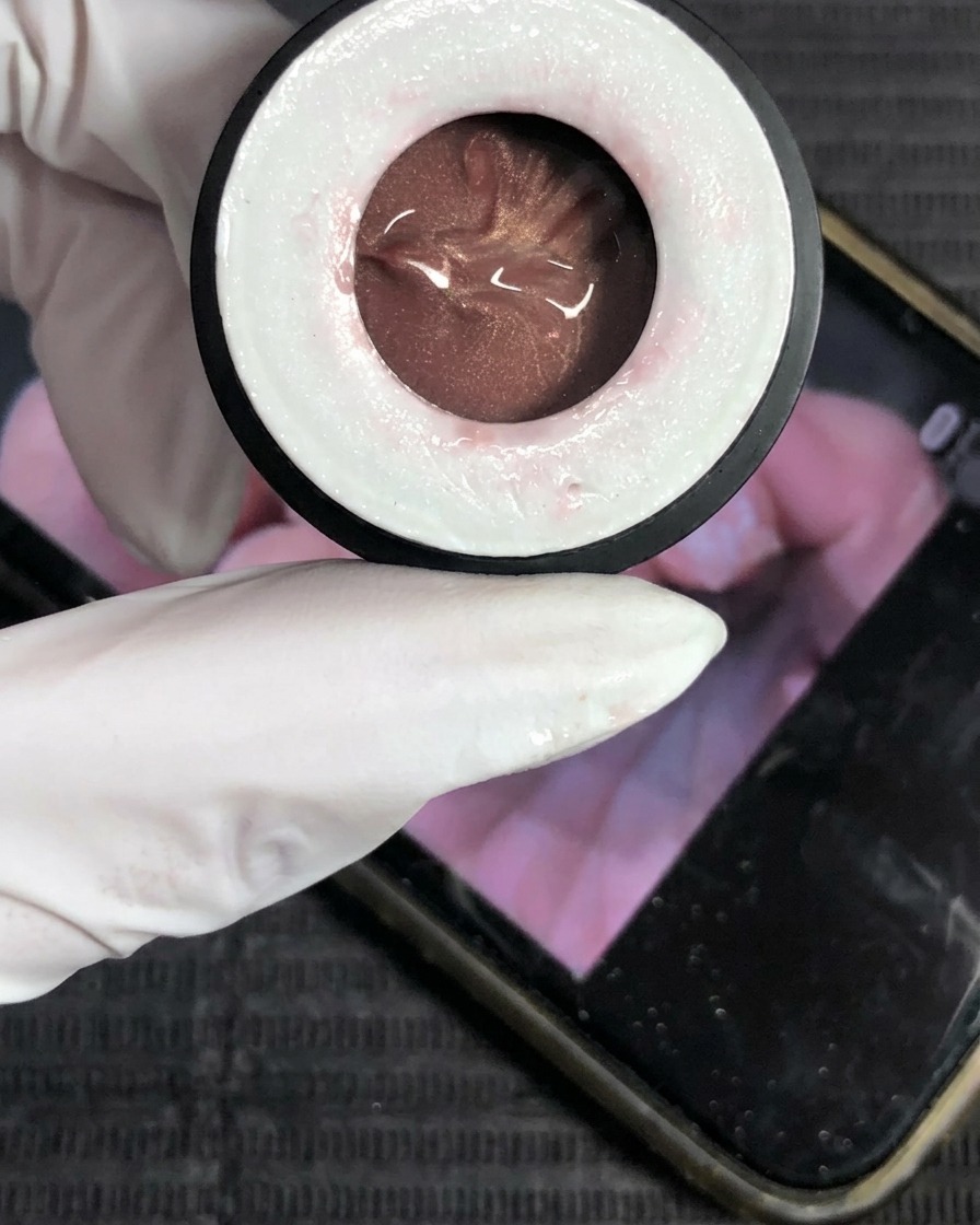 Primer plano de un frasco de esmalte de gel cat-eye color champán.