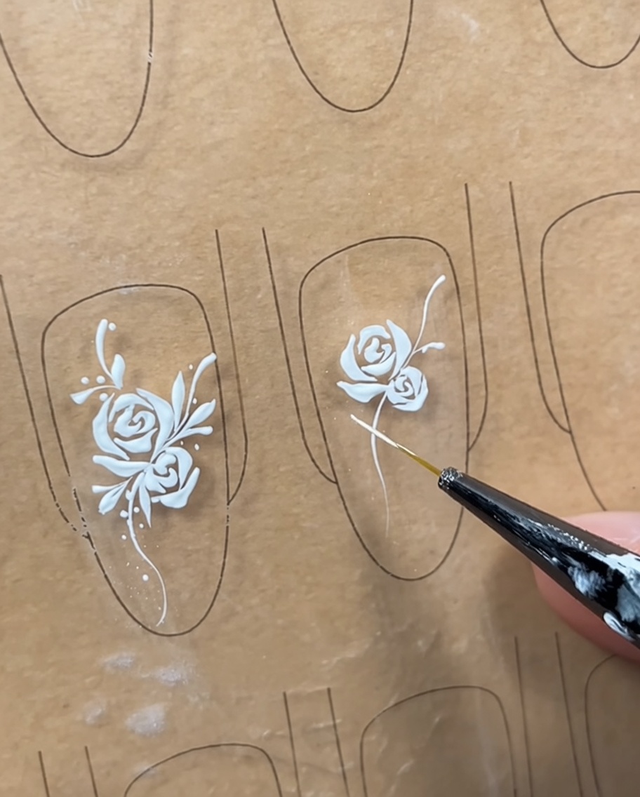Un diseño de uñas con una rosa y una enredadera, con líneas estructurales iniciales dibujadas para marcar dónde se colocarán las hojas.