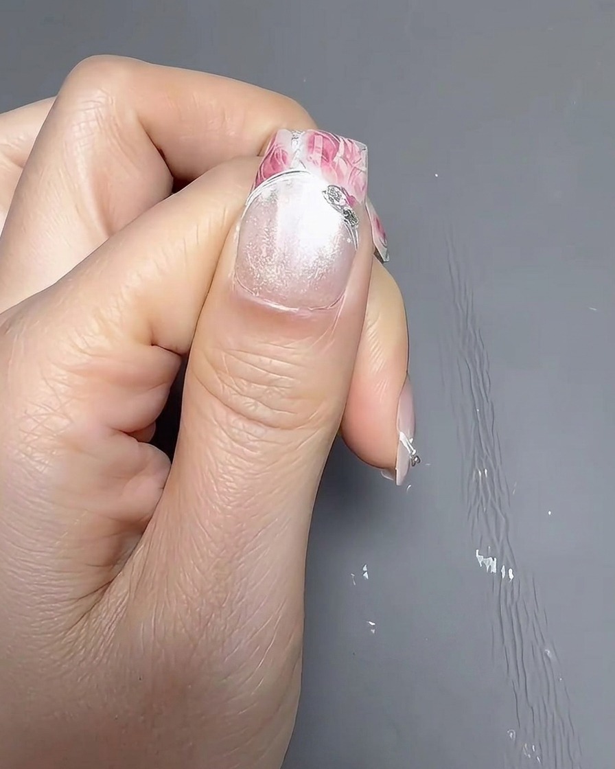 Primer plano de un pincel aplicando una capa suave de esmalte de uñas blanco opaco sobre una uña natural.