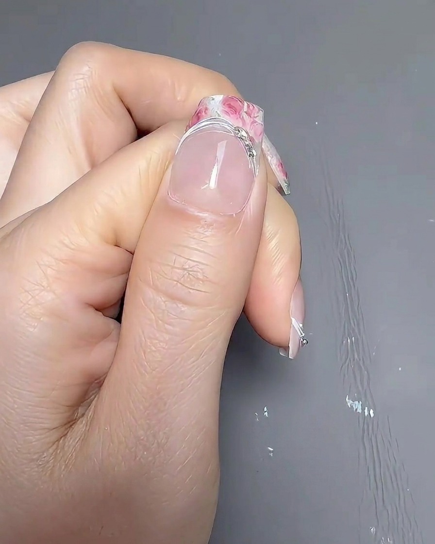 Una mano descansando dentro de una lámpara profesional UV/LED para uñas, con la luz encendida curando las uñas.