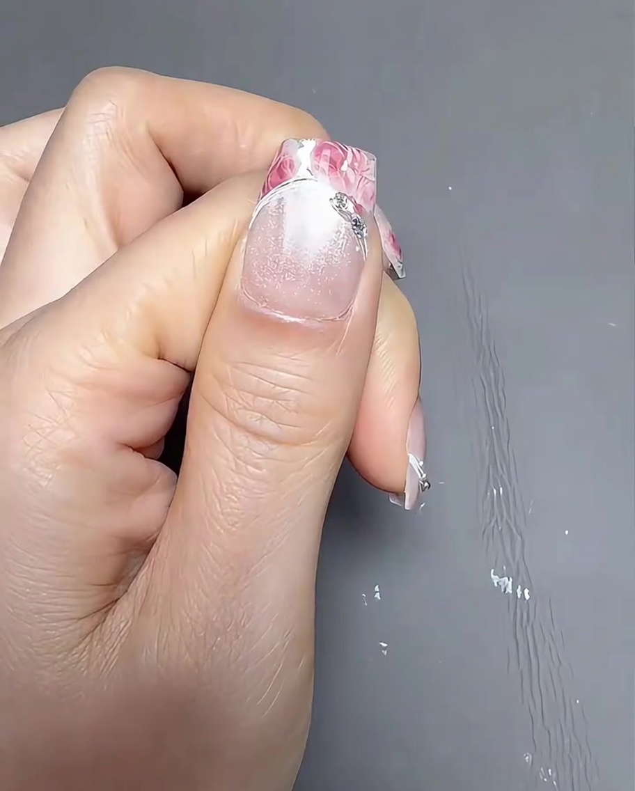 Aplicando un gel de transferencia transparente en la parte de la punta francesa de la uña usando un pincel de detalle pequeño.