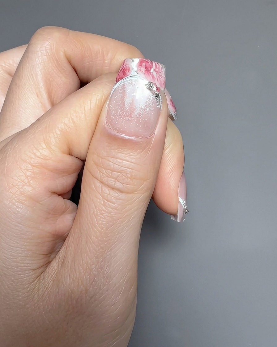Primer plano mostrando una segunda pegatina de rosa siendo cuidadosamente colocada sobre la primera en una uña.