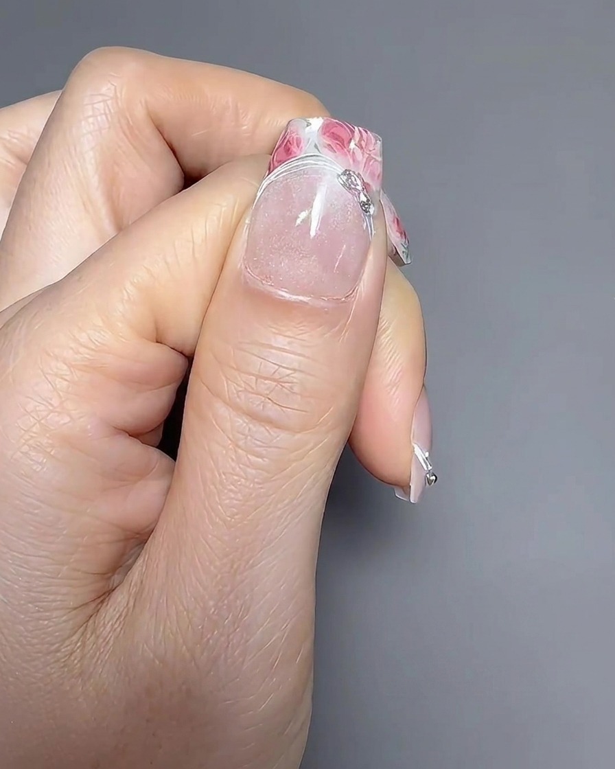 Primer plano de un pincel liner aplicando una fina línea de gel a lo largo de la línea de la sonrisa de una manicura francesa.