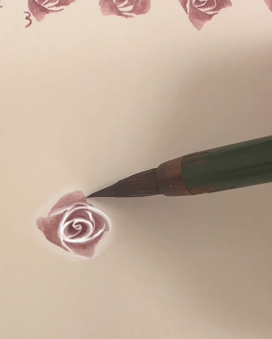 Una rosa de acuarela sobre papel con una cuarta capa de pétalos más grande siendo aplicada.