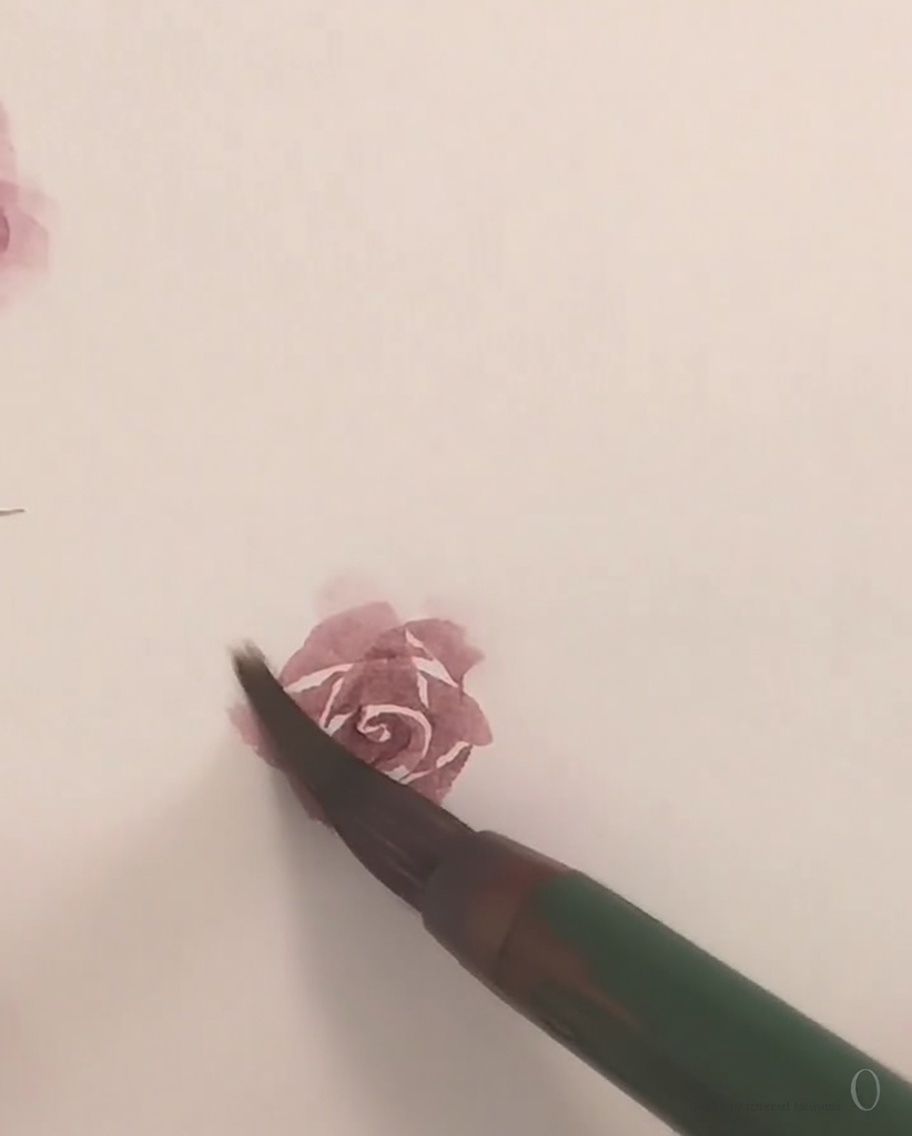 Un pincel pequeño aplicando pintura rosa delicada para formar el pétalo exterior final de una rosa.