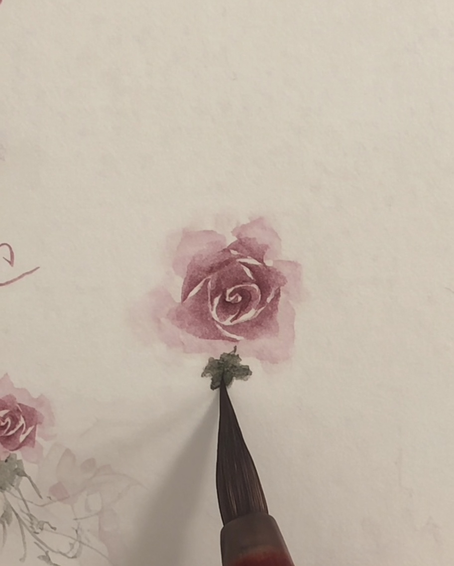Un pincel limpio difuminando ligeramente los bordes de una rosa de acuarela rosa sobre papel blanco.