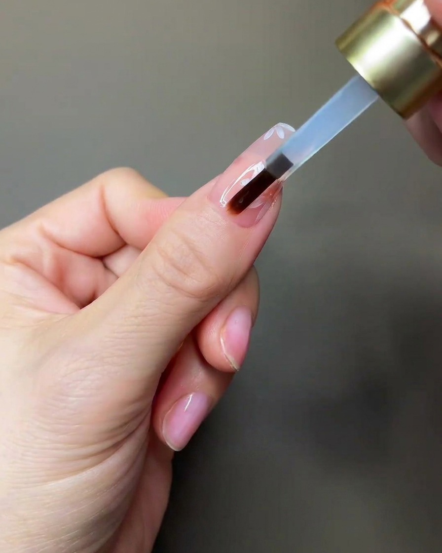 Una mano colocando una uña bajo una pequeña lámpara UV/LED portátil para curar.