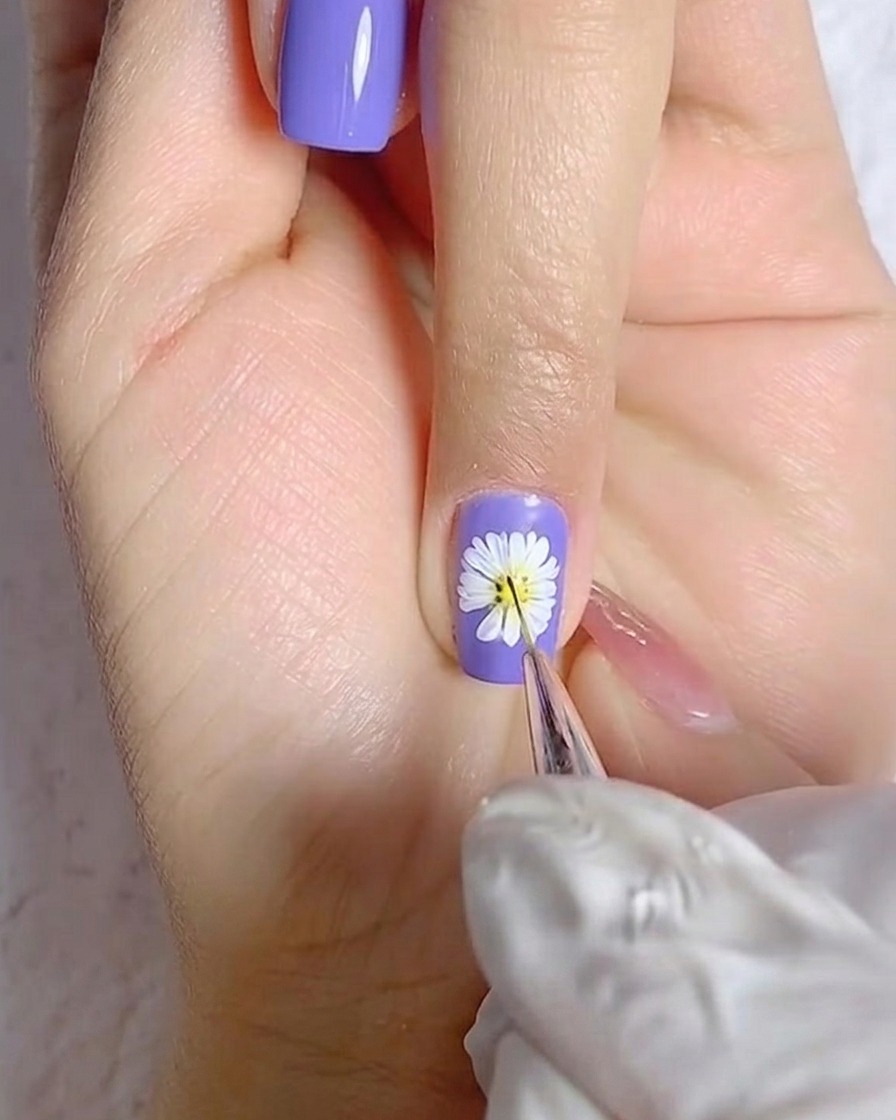 Un pincel aplicando una capa suave de esmalte gel blanco sobre una uña del pulgar.