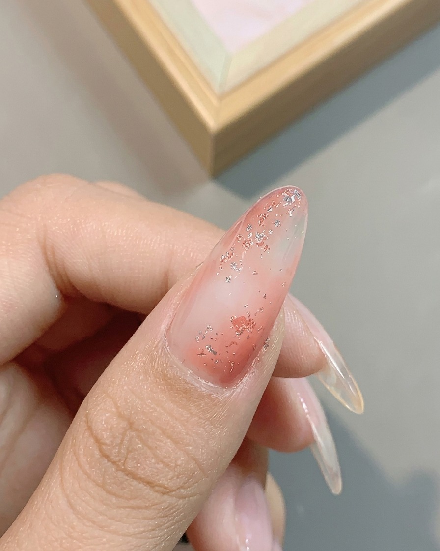 Primer plano del brillo metálico del gel plata platino No. 04 aplicado sobre la uña rosa brillante.