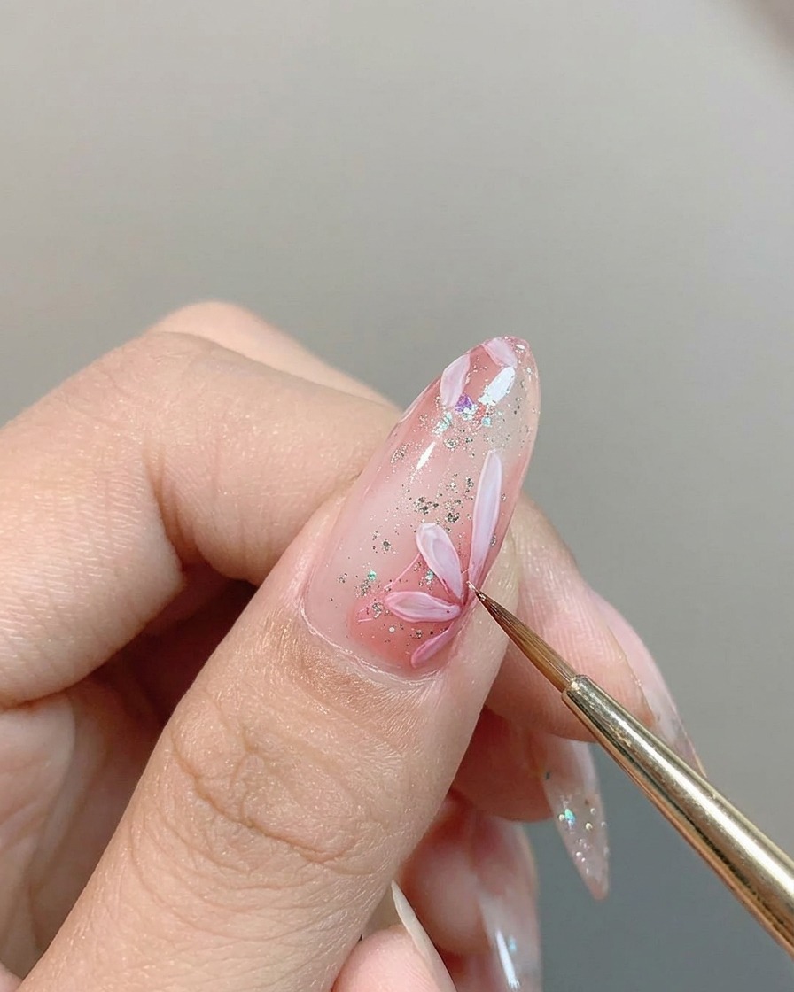 Un pincel fino aplicando un punto de pigmento rosa en el centro de una margarita blanca.