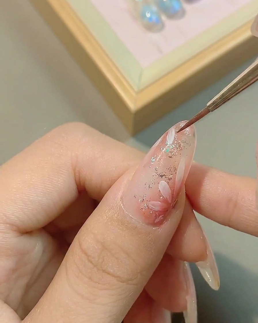 Un pincel aplicando top coat brillante sobre el arte de la margarita terminado.