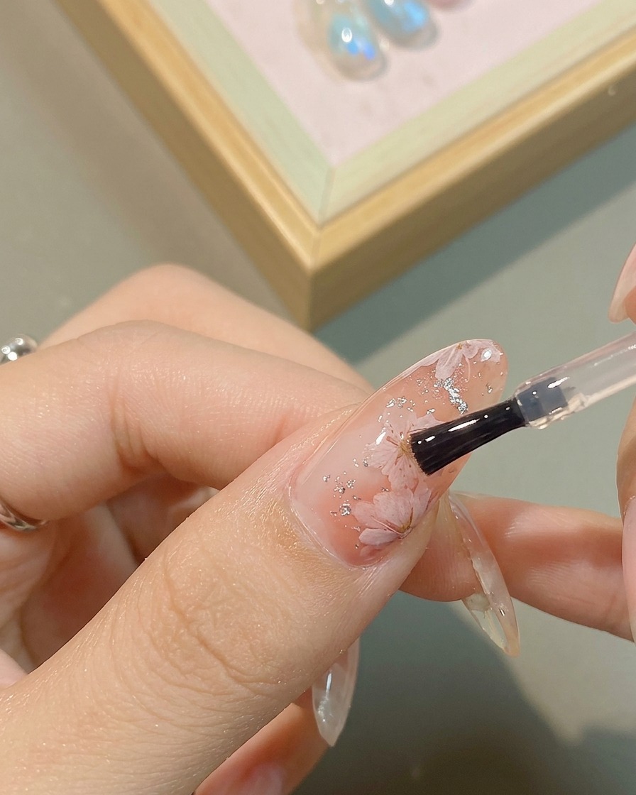 Detalle de gel metálico plateado siendo aplicado en el corazón de la flor pintada.