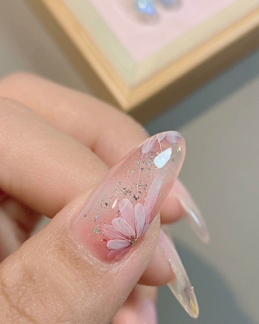 Un pincel aplicando un top coat brillante final sobre el diseño de margarita terminado.
