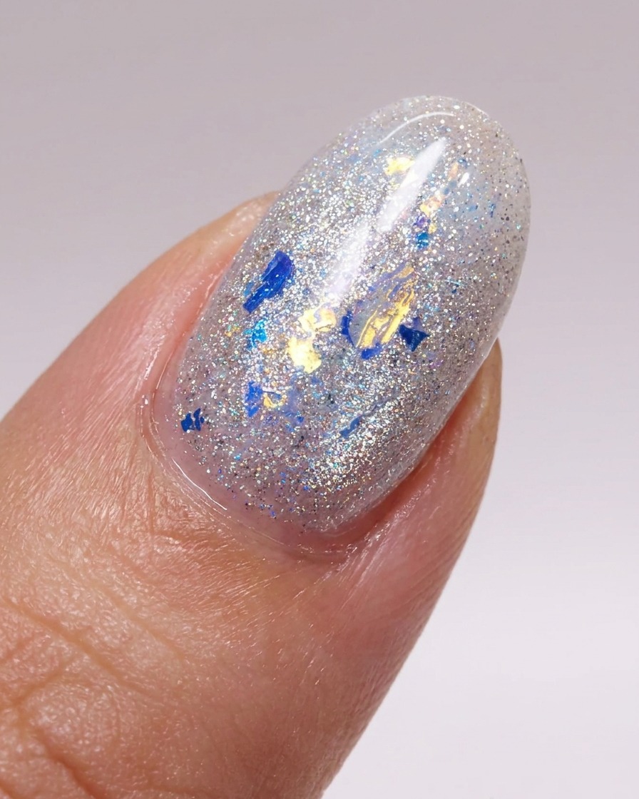 Un pincel aplicando una capa suave de top coat brillante sobre una uña decorada con hojuelas de glitter.